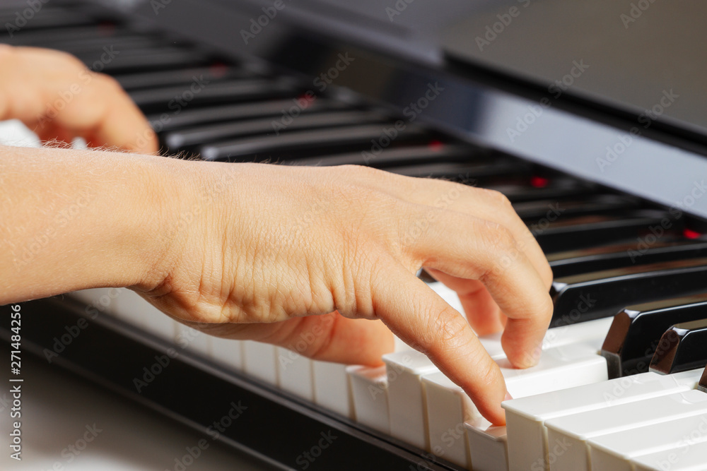 Fototapeta premium Close up view of kid hands playing on piano keyboard