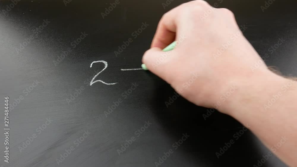 Someone's hand is chalking on the blackboard a mathematical example for children. Back to the school concept. Someone's hand is chalking on the blackboard a mathematical example for children. Back to the school concept.