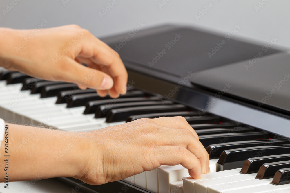 Obraz premium Close up view of kid hands playing on piano keyboard