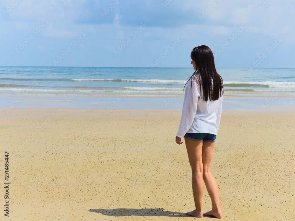young attractive woman on holiday by the sea, tropical beach, in an airy white shirt, looking into the distance, traveling in Thailand, joyful, positive emotion, summer style