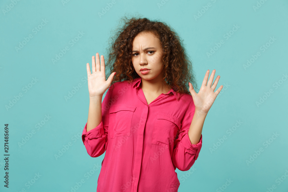 Portrait of concerned african girl in casual clothes rising hands, showing palm isolated on blue turquoise wall background in studio. People sincere emotions lifestyle concept. Mock up copy space. Portrait of concerned african girl in casual clothes rising hands, showing palm isolated on blue turquoise wall background in studio. People sincere emotions lifestyle concept. Mock up copy space.