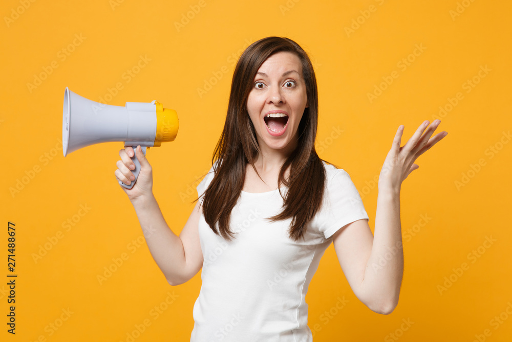 Amazed young woman in white casual clothes keeping mouth open scream in megaphone, spreading hands isolated on bright yellow orange background in studio. People lifestyle concept. Mock up copy space. Amazed young woman in white casual clothes keeping mouth open scream in megaphone, spreading hands isolated on bright yellow orange background in studio. People lifestyle concept. Mock up copy space.