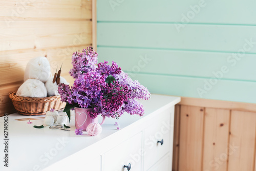 Crochet and knitting. Women s working space. Bouquet of lilac  yarn  crochet hooks on the white dresser in the mint wooden room. Favorite hobby.