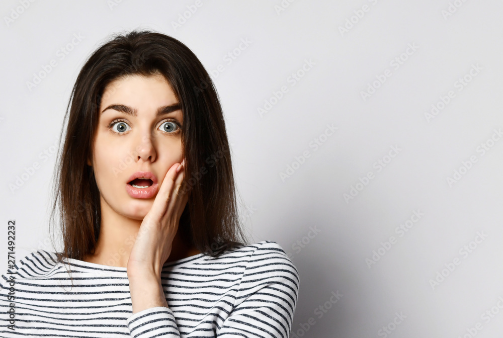 Surprised happy beautiful woman looking straight into the camera with excitement isolated on bright background Surprised happy beautiful woman looking straight into the camera with excitement isolated on bright background