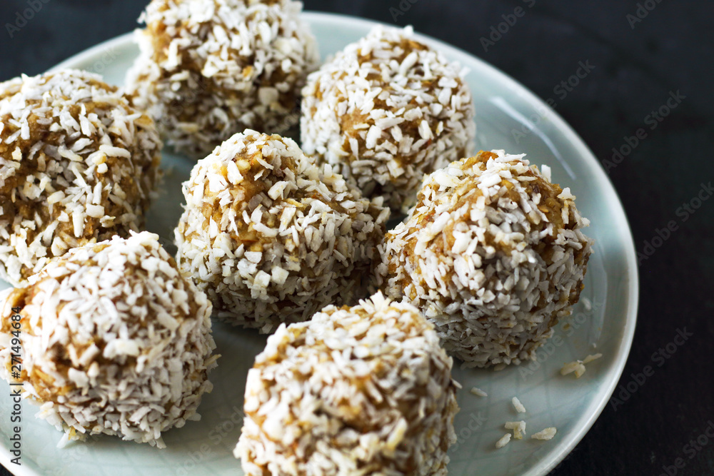 vegetarian raw healthy diet no bake candies dessert sweets without sugar and gluten-free with coconut, proper nutrition snack on blue plate and black slate background, free copy space for text vegetarian raw healthy diet no bake candies dessert sweets without sugar and gluten-free with coconut, proper nutrition snack on blue plate and black slate background, free copy space for text