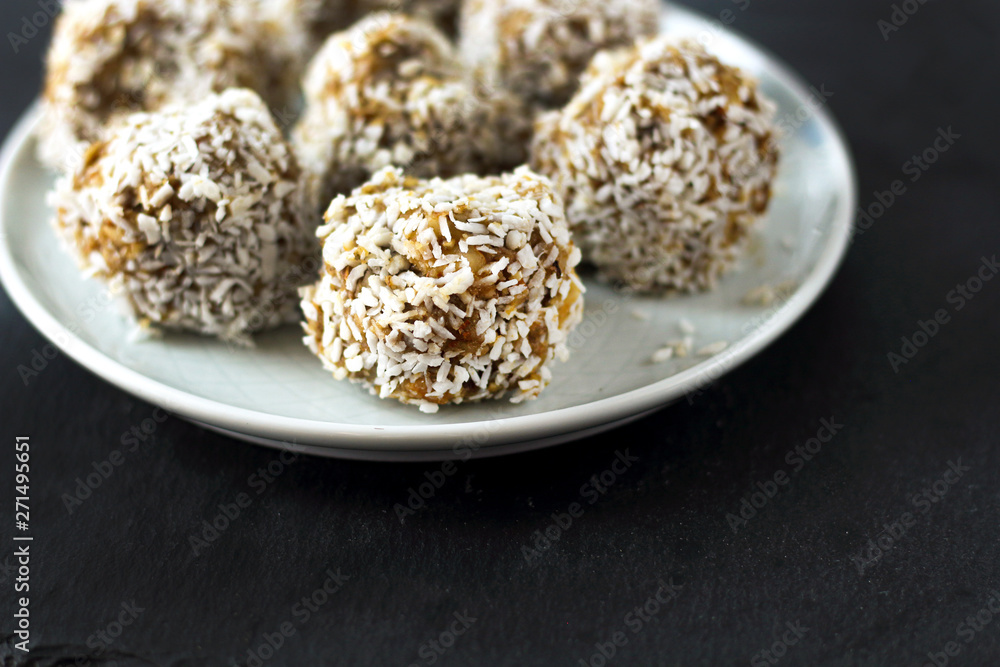 vegetarian raw healthy diet no bake candies dessert sweets without sugar and gluten-free with coconut, proper nutrition snack on blue plate and black slate background, free copy space for text vegetarian raw healthy diet no bake candies dessert sweets without sugar and gluten-free with coconut, proper nutrition snack on blue plate and black slate background, free copy space for text