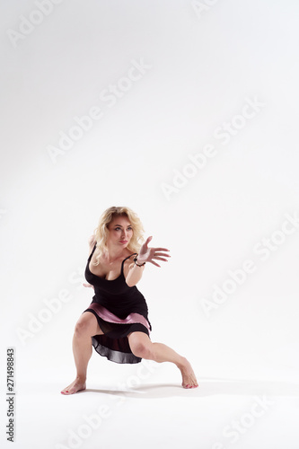 Image of dancing young long-haired woman in black dress in studio