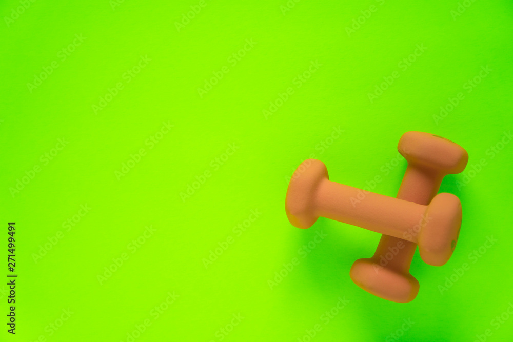 Fitness equipment with womens yellow orange weights/ dumbbells isolated on a lime green with copyspace background with copyspace Fitness equipment with womens yellow orange weights/ dumbbells isolated on a lime green with copyspace background with copyspace