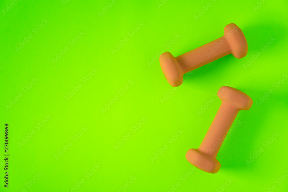 Fitness equipment with womens yellow orange weights/ dumbbells isolated on a lime green with copyspace background with copyspace Fitness equipment with womens yellow orange weights/ dumbbells isolated on a lime green with copyspace background with copyspace
