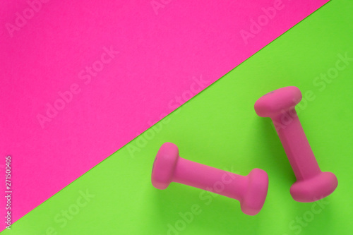 Fitness equipment with womens pink weights/ dumbbells isolated on a lime green and hot pink background with copyspace