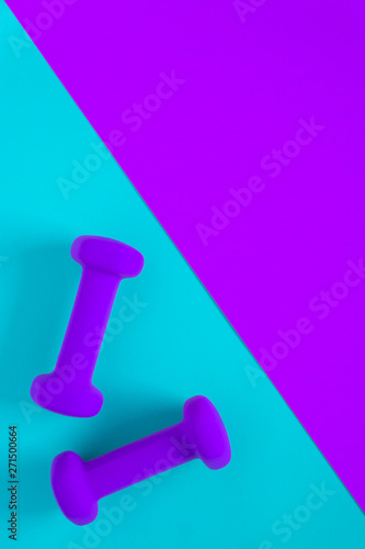 Fitness equipment with womens purple weights/ dumbbells isolated on a light sky blue and purple background with copyspace © Jaimie