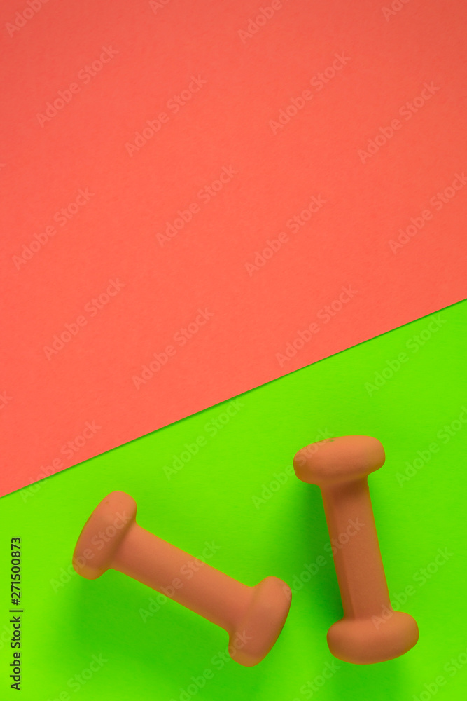 Fitness equipment with womens yellow orange weights/ dumbbells isolated on a lime green and orange with copyspace background with copyspace Fitness equipment with womens yellow orange weights/ dumbbells isolated on a lime green and orange with copyspace background with copyspace