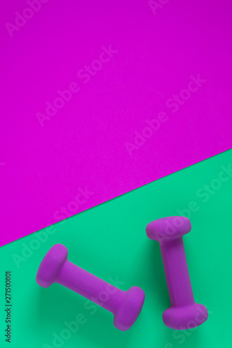 Fitness equipment with womens purple weights/ dumbbells isolated on a teal green background with copyspace © Jaimie