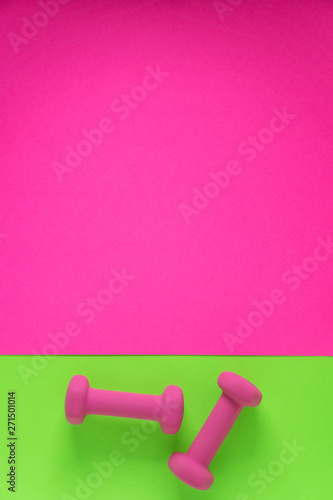 Fitness equipment with womens pink weights/ dumbbells isolated on a lime green and hot pink background with copyspace © Jaimie
