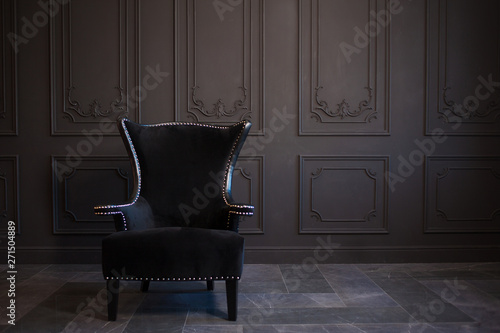 Stylish black chair against a dark gray wall
