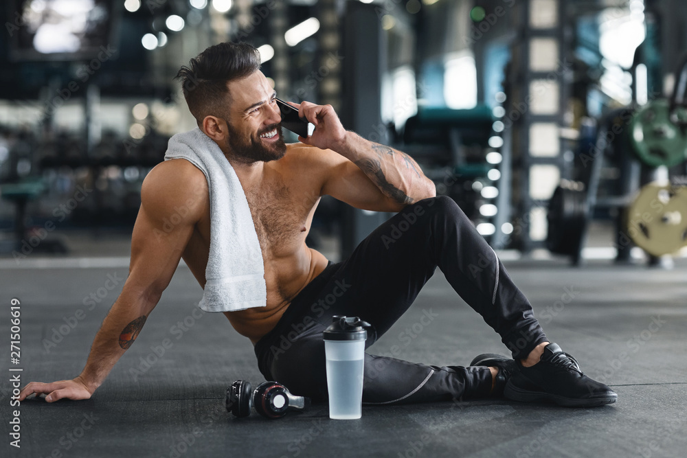Muscular guy talking on cellphone after training at gym Muscular guy talking on cellphone after training at gym