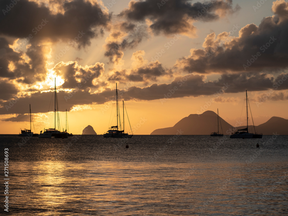 Sailboats in tropical laggon with the sunsetting behind the clouds and masts Sailboats in tropical laggon with the sunsetting behind the clouds and masts