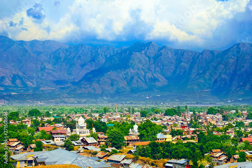 Beautiful city scape, traditional kashmiri houses and sikh temple in green valley against the background of colorful mountain range and sky in Srinagar, Himalayas, Jammu & Kashmir, India