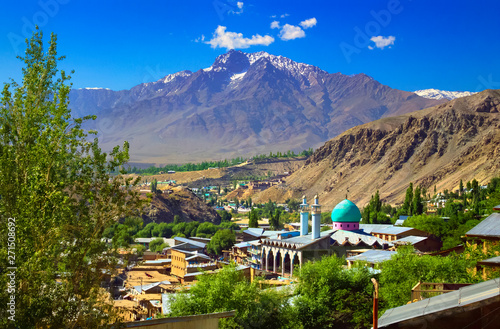 Beautiful city scape - traditional houses and mosque with emerald green cupola against the background of mountain range and blue sky in Kargil, Himalayas, Ladakh, Jammu & Kashmir, Northern India photo