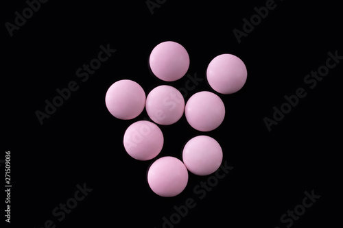 Several light pills on black background top view