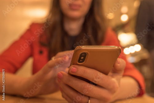 married businesswoman with painted nails looks at her phone while sitting down at a table inside of a restaurant