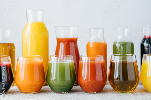Set of glass jars with multicolored drinks standing in row. Fresh juice made of different fruit isolated over white background. Summer drink
