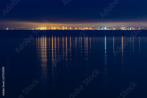 night city lights in the reflection on the beach