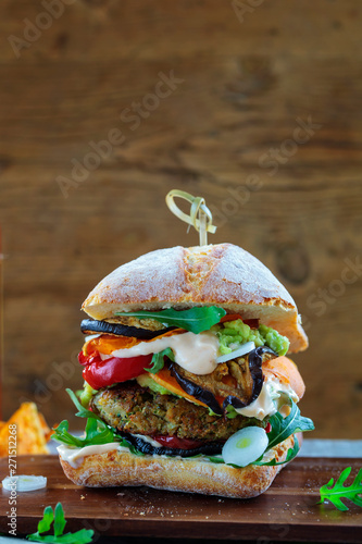 Vegetarian burger made of mushrooms, chickpeas and broccoli with roast pepper, aubergines, rocket leaves and avocado mash