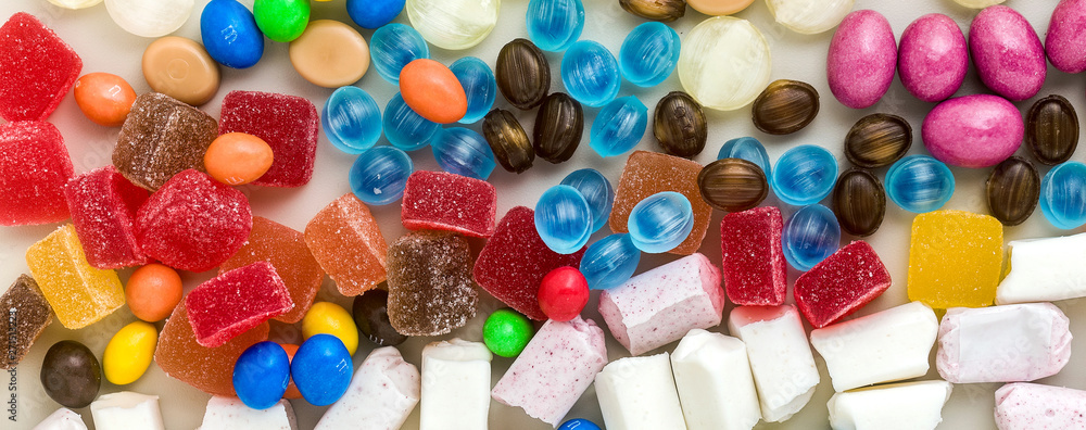 banner of multicolored caramel candies scattered on the table background. sugar products. colored sweets banner of multicolored caramel candies scattered on the table background. sugar products. colored sweets