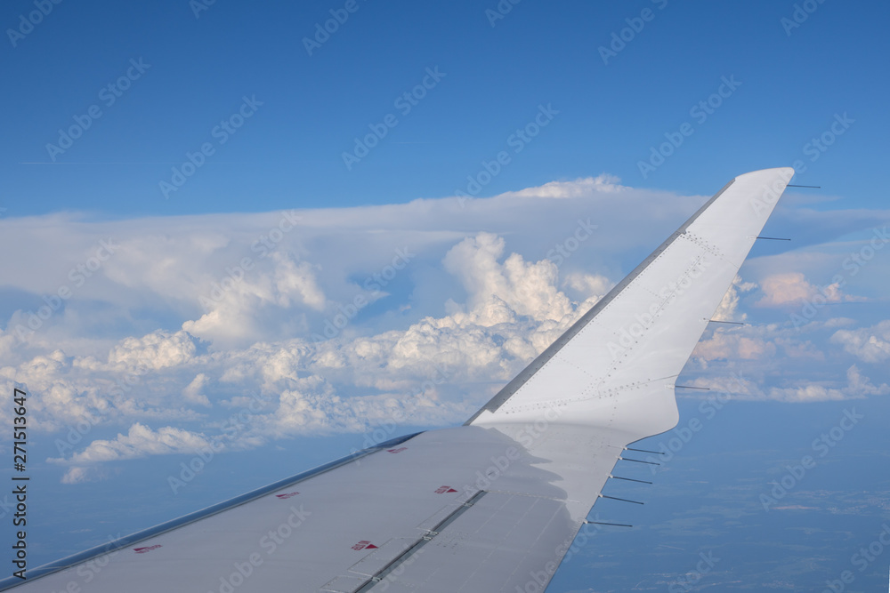 In-flight view on aircraft winglet with blue sky above clouds