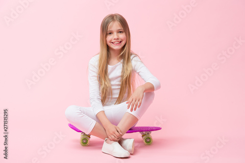 Ride penny board and do tricks. Girl likes to ride skateboard. Active lifestyle. Girl having fun with penny board pink background. Kid adorable child long hair adore ride penny board. Happy childhood