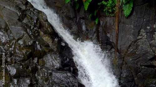 Amazing slow motion closeup shot of a waterfall flowing down a rocky edge and into a clear water pound photo