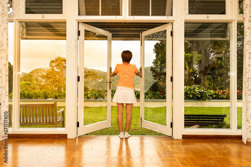 Women opening glass door to refreshing sunrise with greenaries