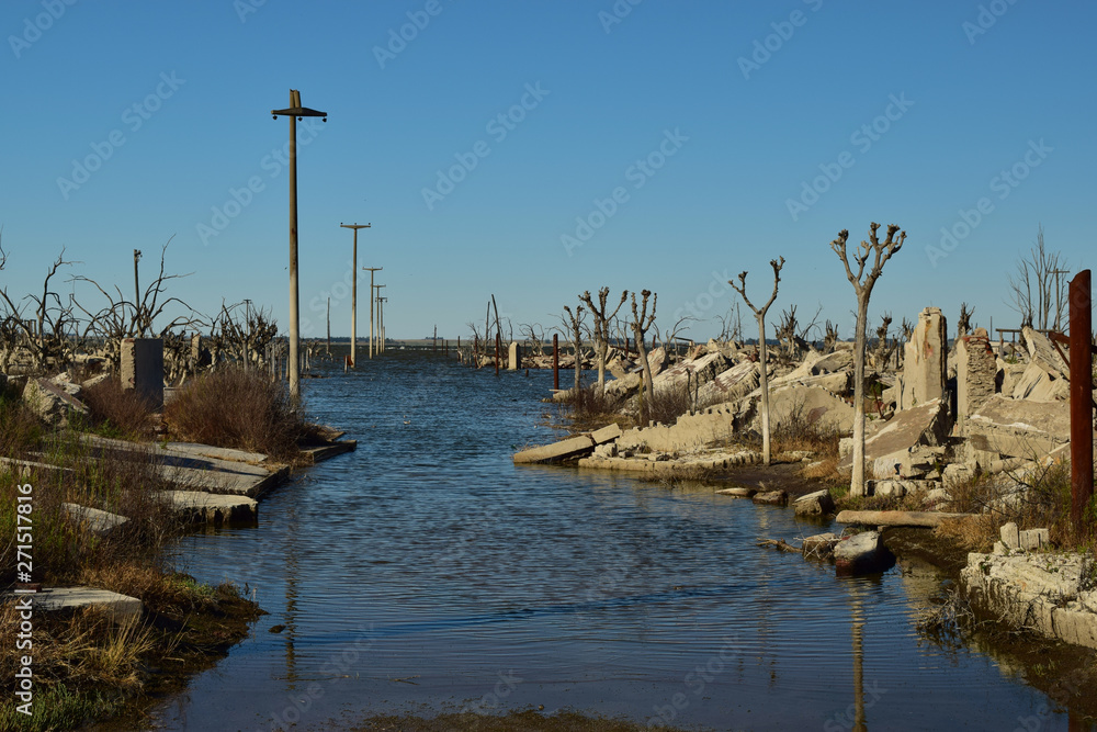 calle llena de agua con las casa en ruinas a su costado