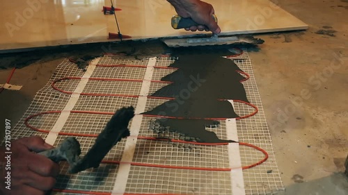 Installation of heated floor. Laying a ceramic or porcelain tile floor close-up. Worker laying slab. Repair in the apartment.