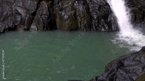 Splendid shot of a small lake with a waterfall in the corner flowing intensely photo