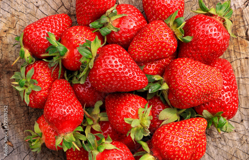Red and ripe large strawberries on a wooden surface. Close-up. Harvest.