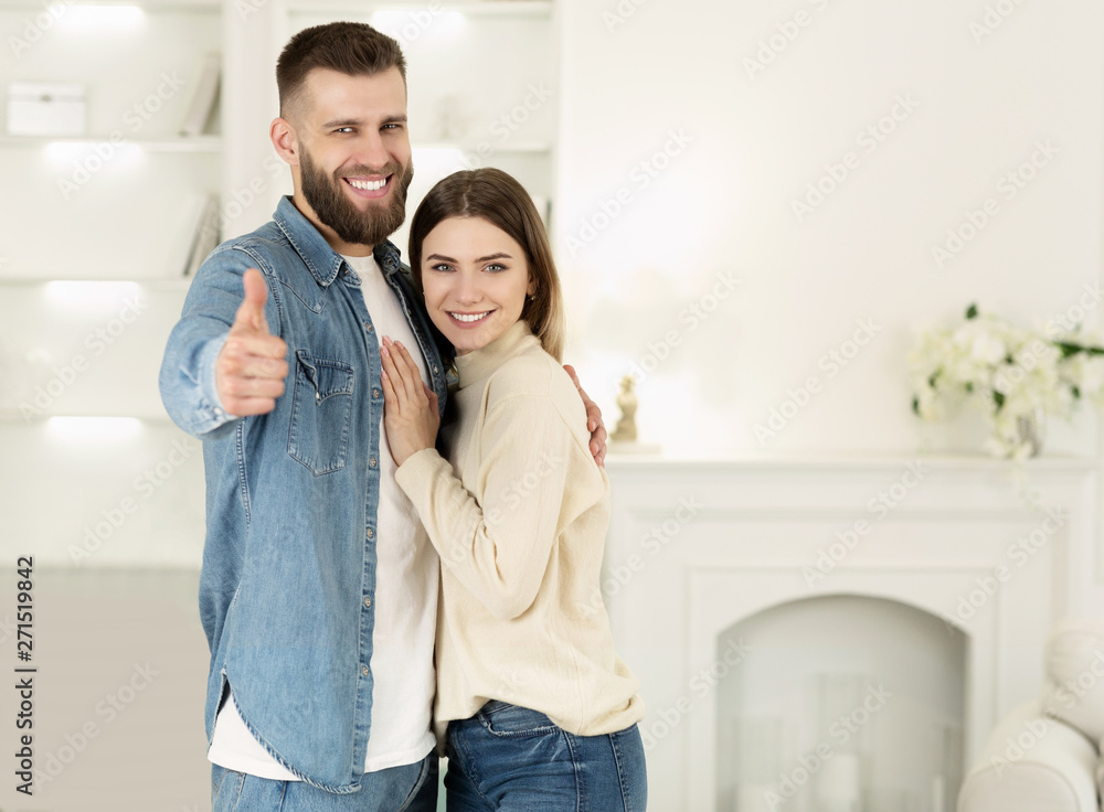 Couple Hugging In New Apartment, Man Showing Thumb Up Couple Hugging In New Apartment, Man Showing Thumb Up