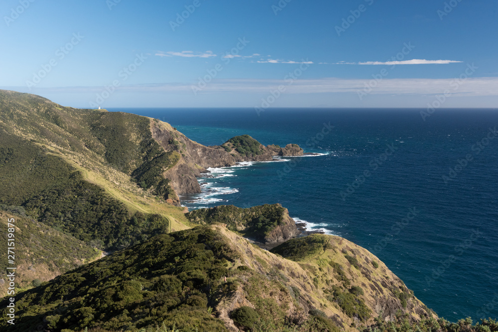 Elevated view of the rocky, Pacific coast of Cape Reinga, with the lighthouse visible in the background. Northland, New Zealand.