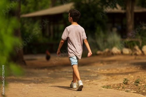 Little kid boy walking alone in the forest. The path to life. Bullying in school concept. Fright and fright. Back view
