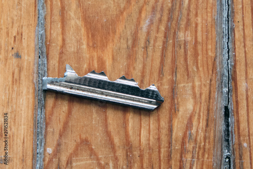 Broken key on old wooden background. The tongue is a broken rusty key from door lock.