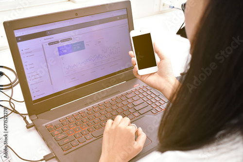 Webmaster check website analytics on dashboard and holding her smartphone