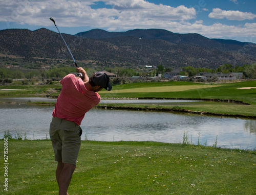 Male Golfer Hitting a Ball Off of the Tee Box - Mountains in the background