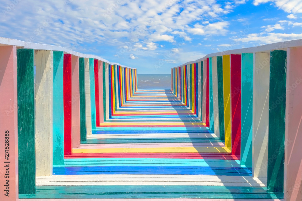 The colorful wood bridge extends into the sea in Cloudy sky - obrazy, fototapety, plakaty 