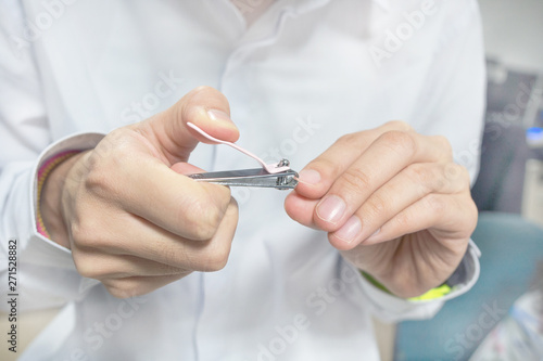 Close up of man is cutting his nails by Clippers