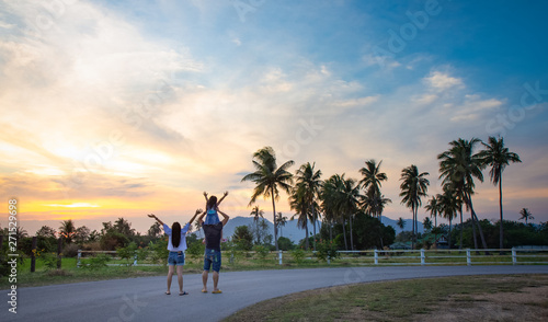 Happy Parents and Daughter are traveling on natural scenery at sunsetn in thailand.Family concept photo
