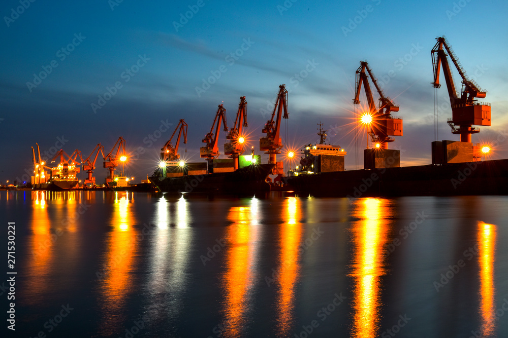 Fototapeta premium Night, cranes at harbour docks are busy working