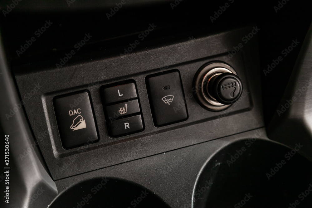 Сlose-up of the car black interior: off road, headlight washer, seat heatting adjustment buttons and cigarette lighter Сlose-up of the car black interior: off road, headlight washer, seat heatting adjustment buttons and cigarette lighter