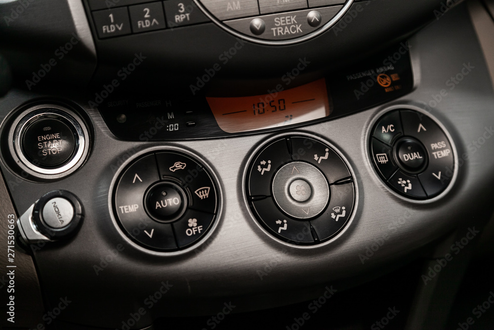 Сlose-up of the car black interior: dasboard with clock, start engine buttons, adjustment of the blower, air conditioner and other buttons. Сlose-up of the car black interior: dasboard with clock, start engine buttons, adjustment of the blower, air conditioner and other buttons.