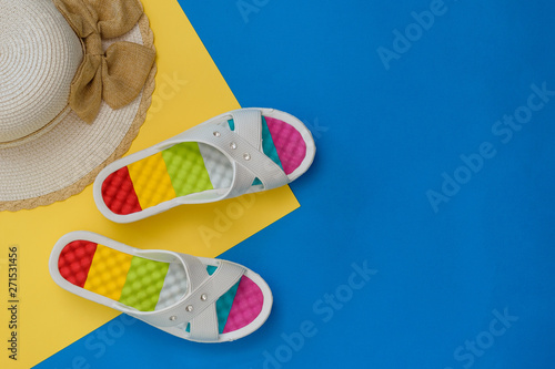 Hat and colorful shoes for women on blue and yellow background. The concept of a holiday by the sea. Flat lay.